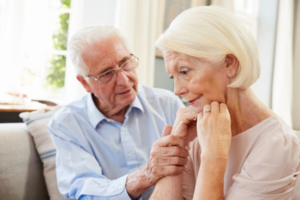 Senior man comforting a woman with dementia at home.